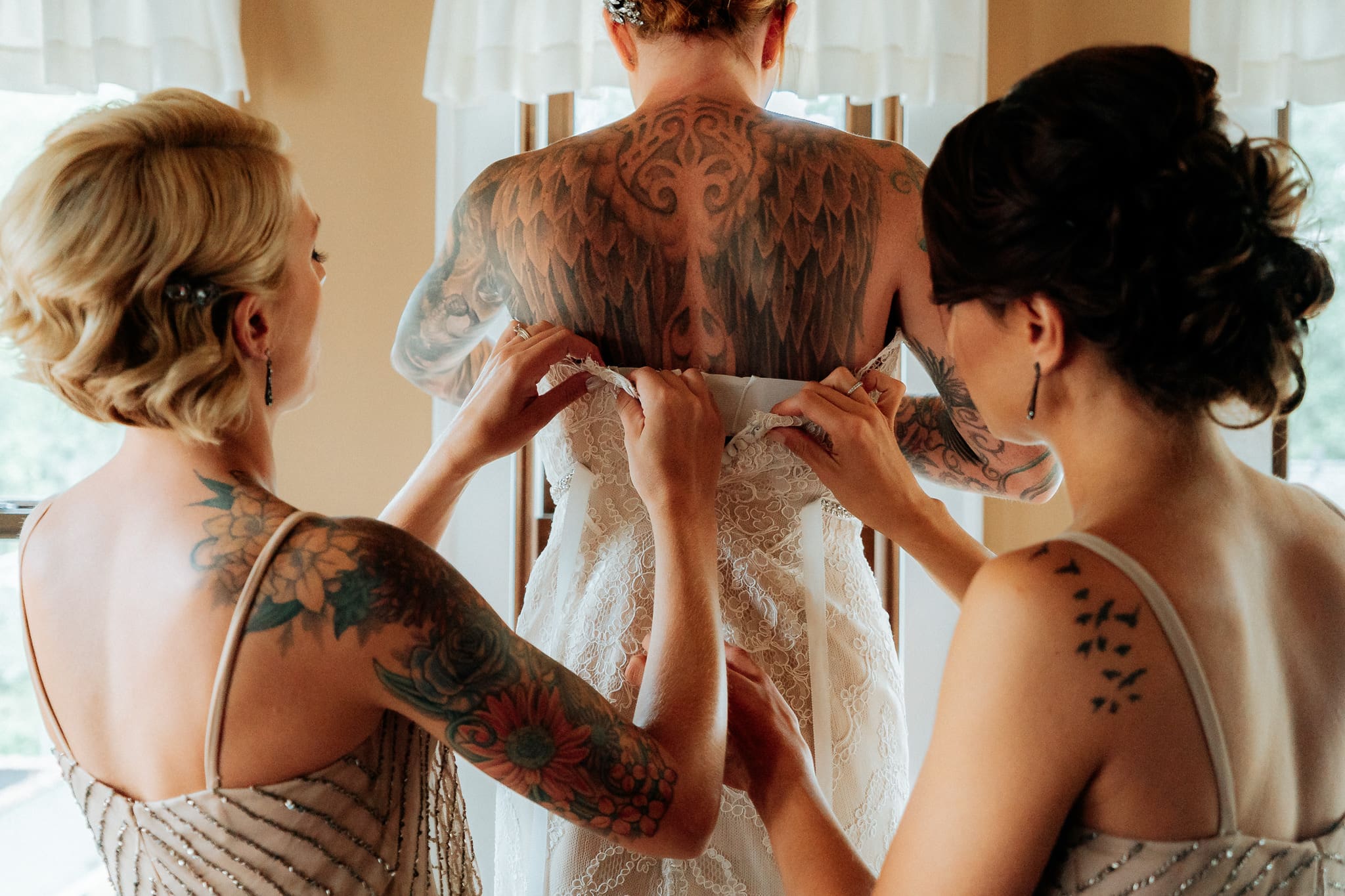 bridesmaids help put a wedding dress on a bride