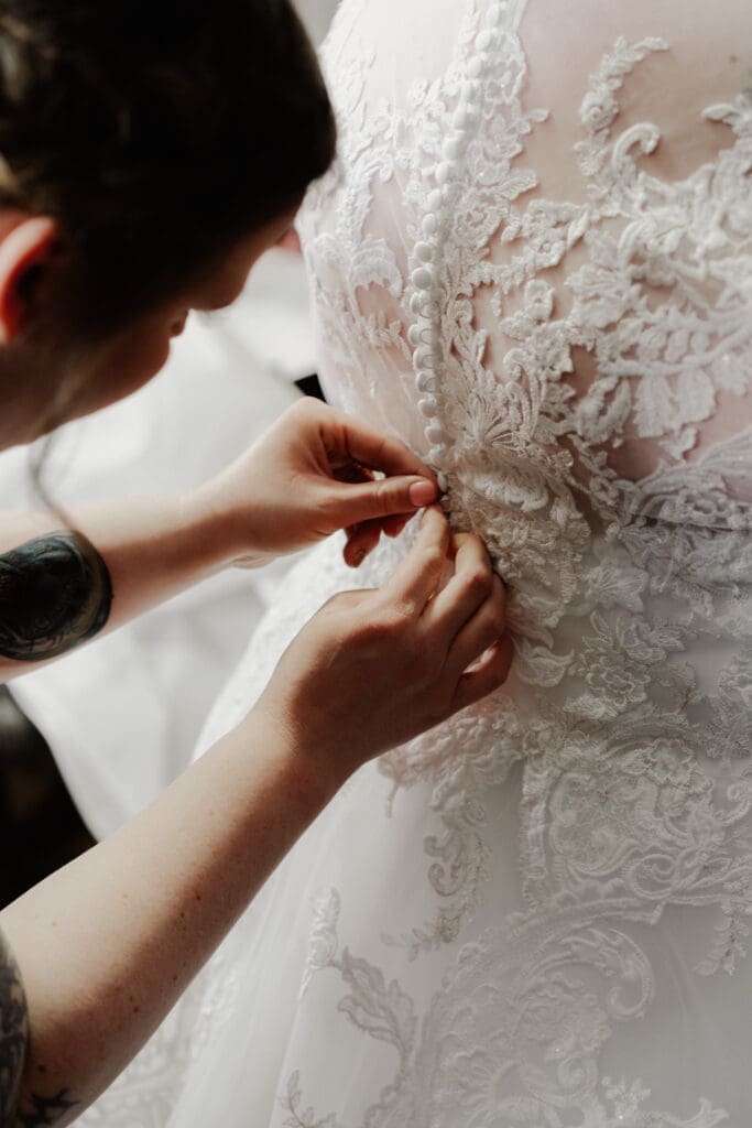 hands buttoning a wedding dress to prepare for a wedding